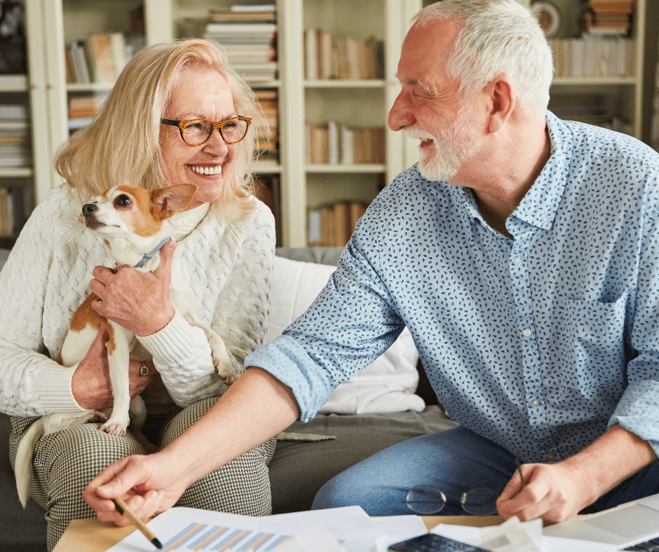 Elderly man smiling at woman with a small dog in her lap