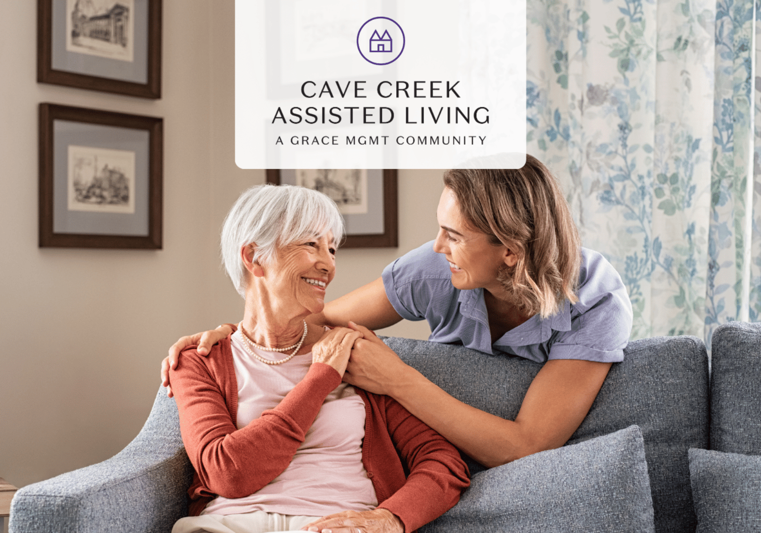 Elderly woman smiles on a sofa while a caregiver sits beside her in a cozy living room; banner reads Cave Creek Assisted Living.